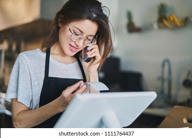 Shop Assistant Taking Order On Phone In Restaurant