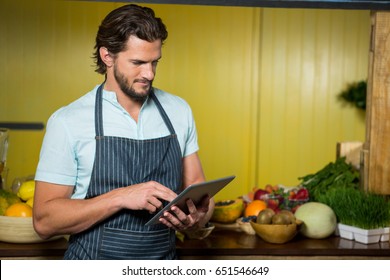 Shop assistant using digital tablet in health grocery shop - Powered by Shutterstock