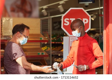 Shop employee at the entrance of the supermarket spraying disinfectant on customers hands for safety measures during covid-19 - Shutterstock ID 1713114652