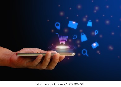 Shop online concept. Hand hold smartphone with shopping cart, search, credit card and bag virtual icon on blue background. Quarantine to save life from corona virus.  