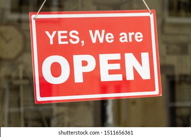 Shop Sign With Yes, We Are Open Written On It And A Reflection