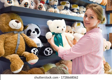 Shop soft toys. The buyer chooses the toy. A woman buys a Teddy bear. gift for child
