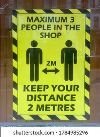 A Shop Window Has A Sign Indicating People Must Be 2 Metres Apart And Maximum 3 Persons At One Time .