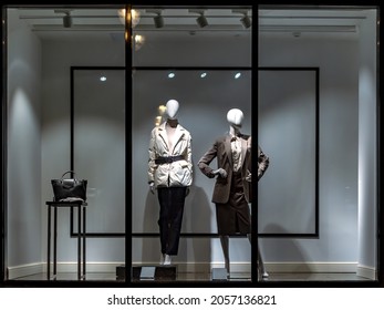 Shop windows and mannequins. Fashion Store exterior. City Night Boutique. Front View from street outdoor. LED light. City facade background