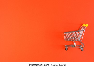 Shopaholic. Buyer. Shopping concept. Close-up. From above. Isolated shopping trolley on a red background. Copy space.