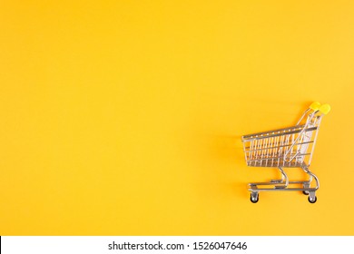 Shopaholic. Buyer. Shopping concept. Close-up. From above. Isolated shopping trolley on a yellow background. Copy space.