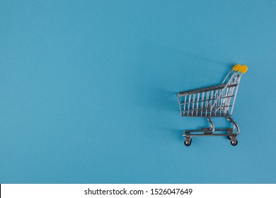 Shopaholic. Buyer. Shopping concept. Close-up. From above. Isolated shopping trolley on a blue background. Copy space.