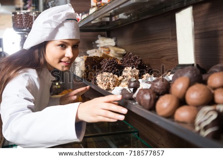 shopgirl posing with delicious chocolate and cakes for sale in cafe