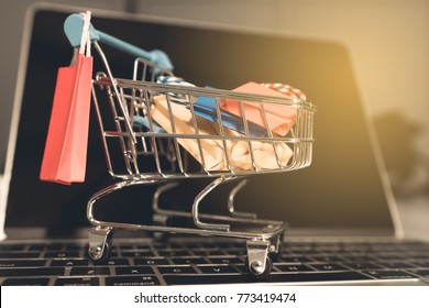 Shoping Online Concept, Colorful Paper Shopping Bag In Trolley On Laptop. Customer Can Buy Everthing From Office Or Home And The Messenger Will Deliver.