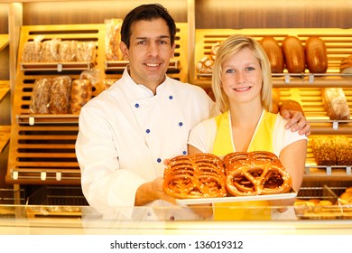 Shopkeeper and baker in Bakery or baker's shop present a tablet full of pretzels - Powered by Shutterstock