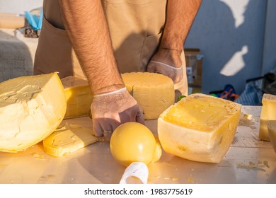 Shopkeeper's Hands Cutting A Head Of Cheese Close Up. Artisan Cheese In A Street Market. Cheese Maker Cutting Cheese In His Workshop. Food Festival In The City Park. Street Fast Food.