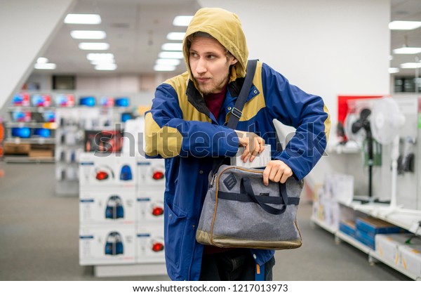shoplifter in the electronic store supermarket\
stealing new gadget