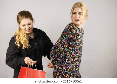 Shoplifting is a crime. Young fashionable woman being caught on stealing clothes by female security guard. Customer being thief.