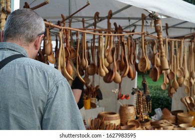 The Shopper Chooses To Buy A Product At The Craft Fair. Wooden Spoons And Other Articles Of Wood In The Craftsman Market.