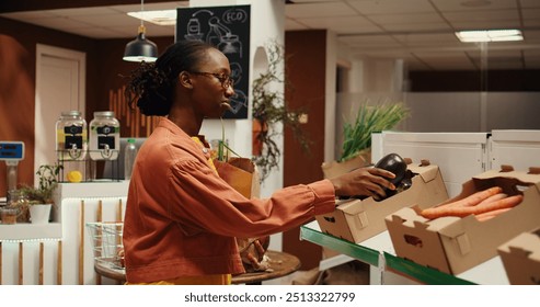 Shopper choosing freshly harvested vegetables from market, eating healthy and buying produce from local zero waste eco store. African american client shopping for organic food items. Camera 2. - Powered by Shutterstock