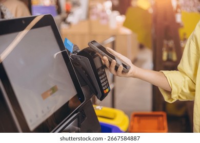 Shopper making a contactless payment using a smartphone at a self service checkout in a grocery store