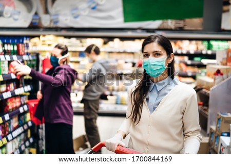 Shopper with mask safely buying for groceries due to coronavirus pandemic in grocery store.COVID-19 shopping.Quarantine preparation.Panic buying and stockpiling.Lockdown.Safety measures in supermarket