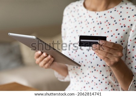 Shopper using tablet for buying on internet stores, paying for purchase by credit card. Customer shopping, ordering, booking online, using bank app or service for payment with keeping data safety