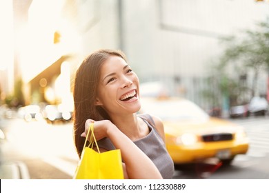 Shopper Woman On Manhattan, New York City Shopping Having Fun Laughing Outside In Streets Of New York. Fresh Blissful Mixed Race Asian / Caucasian Girl Holding Shopping Bag.