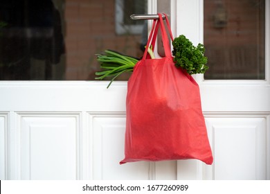 Einkaufstasche mit Waren und Nahrung hängt an der Haustür, Nachbarschafts-Hilfe-Konzept zur Quarantänezeit wegen Koronavirus-Infektion, Kopienraum, selektiver Fokus
