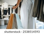 Shopping bags in hand. Close up view of woman that is chooses clothes in the retail shop.