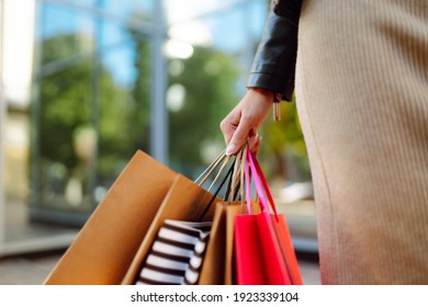 Shopping bags in the woman hands. Young woman after shopping on the city street. The joy of consumption, Purchases, black friday, discounts, sale concept.