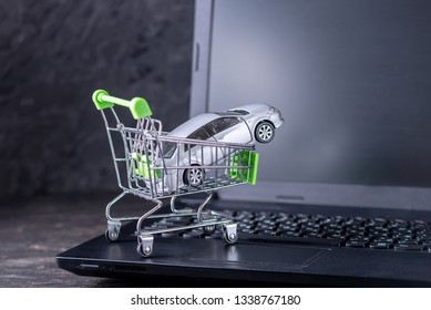 Shopping Basket With Car On Laptop Keyboard On Dark Background. The Concept Of Online Shopping Vehicles On The Internet