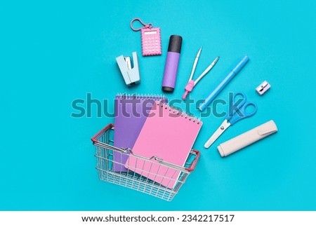 Shopping basket with different school stationery on blue background