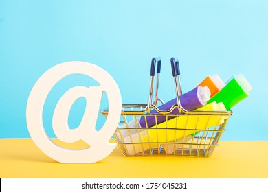 A Shopping Basket Highlighter Marker Pen And At Symbol Or Commercial At On A Yellow And Blue Background. Back To School. Online Shopping.