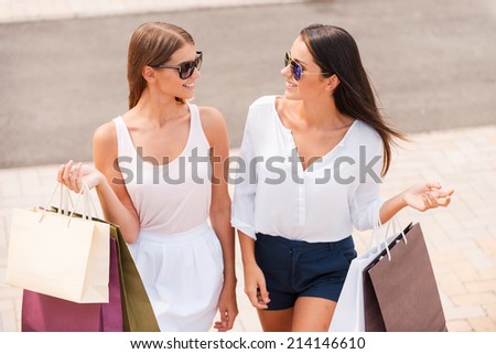 Shopping is the best therapy. Top view of two beautiful young women with shopping bags walking together and talking