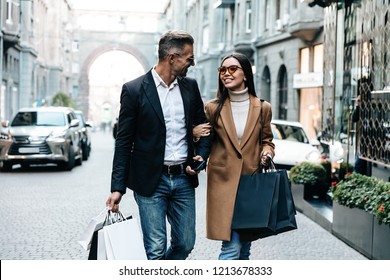 Shopping. Black Friday. Couple. Love. Man and woman with shopping bags are talking and smiling while walking down the street