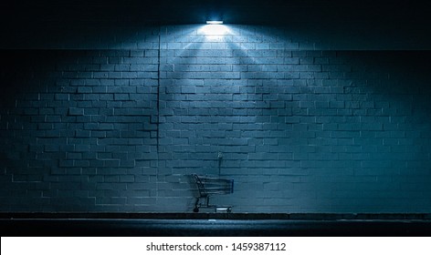 Shopping cart abandoned in the dark under outdoor light - Shutterstock ID 1459387112