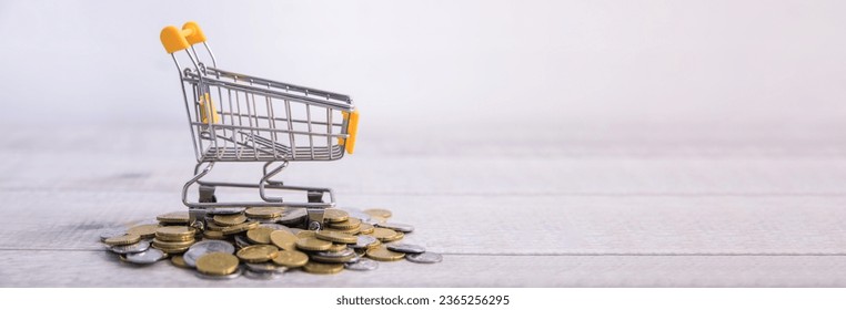 shopping cart or basket with coins - Shutterstock ID 2365256295