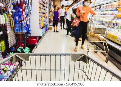 Shopping Cart With Blurred People In Face Mask In Super Market Covid-19 Social Distancing.