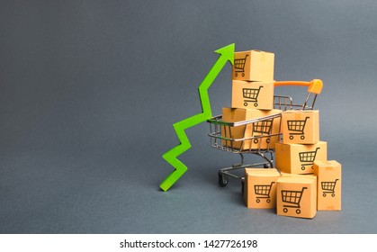 Shopping cart with cardboard boxes with a pattern of trading carts and a green up arrow. Increase the pace of sales, production of goods. Improving consumer sentiment. Strategy for increasing revenue - Shutterstock ID 1427726198