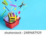 Shopping cart and different flying school stationery on light blue background