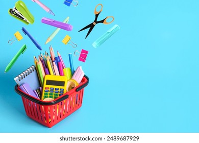 Shopping cart and different flying school stationery on light blue background - Powered by Shutterstock