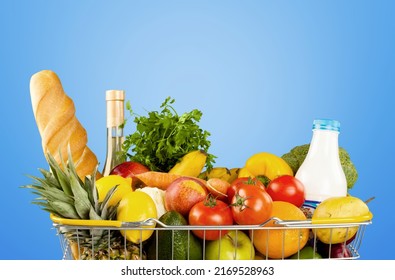 Shopping cart full of fresh groceries, grocery shopping concept on background