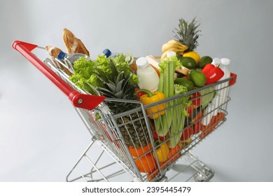 Shopping cart full of groceries on grey background - Shutterstock ID 2395445479
