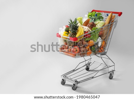 Shopping cart full of groceries on grey background. Space for text