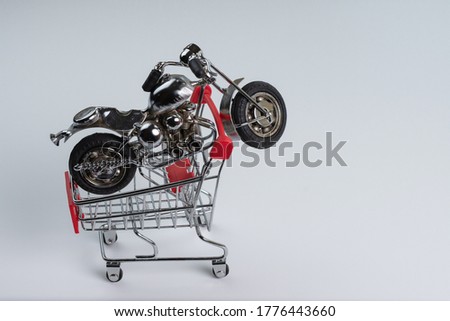 Shopping cart with miniature motorcycle on a white background, motorcycle purchase concept.