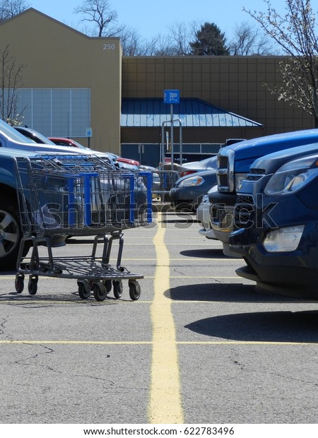 Shopping cart on a\
parking lot with cars