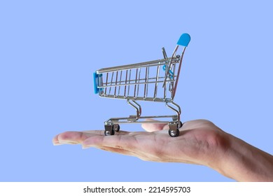 Shopping Cart In People's Hand Isolated On Blue Background. Sales Strategy Concept. Shopping Promotion Concept.