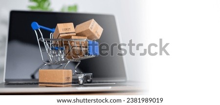 Shopping cart and product boxes placed on laptop computer represent online shopping concept, website, e-commerce, marketplace platform, technology, transportation, logistics and online payment concept