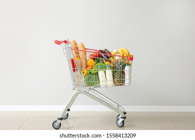 Shopping cart with products near light wall