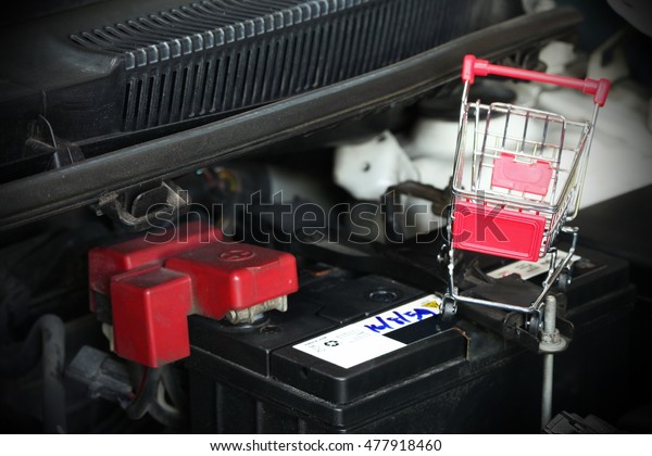Shopping\
cart put on the car battery represent the car battery maintenance\
and car part background concept related\
idea.