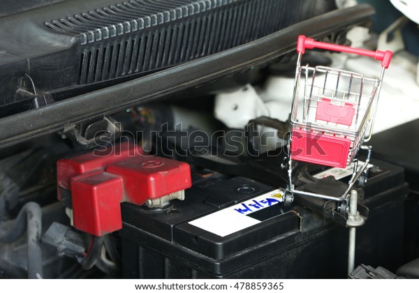 Shopping\
cart put on the car battery represent the car battery maintenance\
and car part background concept related\
idea.