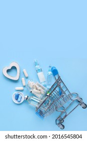Shopping cart with various medicinal pills on a blue background. Creative idea for pharmacy, online pharmacy, health behavior and pharmaceutical company business concept.