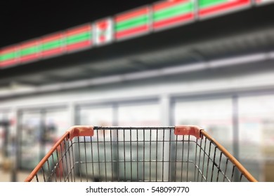 Shopping Cart View In Supermarket In Front Of Abstract Blur Background Of Front Of Convenience Store At Night View, Urban Lifestyle Concept.