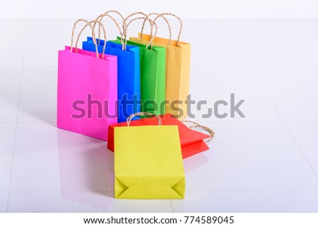Shopping concept : Six color paper shopping bags with jute twined hemp rope handle, all lying on a white floor i.e pink, blue, green, cream, red, yellow. Paper bags are more eco friendly than plastic.